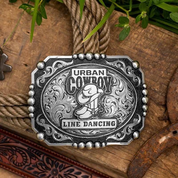 A custom men's silver belt buckle for Urban Cowboy Line Dancing featuring its custom logo 